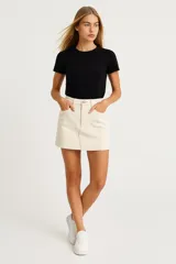 Minifalda negra de jean con bolsillos delanteros y traseros, y ruedo desflecado.