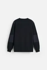 Sweater negro de punto con cuello redondo y manga larga. Presenta parches combinados a tono en hombros y codos.