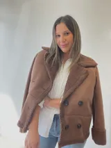 Chaqueta marrón con forro tipo corderito, doble botonadura y cuello con solapas.