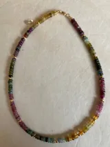 Gargantilla de cuentas facetadas de turmalina multicolor con detalles de pequeñas cuentas doradas y cierre de mosquetón dorado.