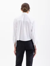 Camisa blanca de manga larga con cuello clásico y botones de diferentes colores.