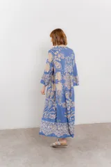 Vestido largo azul con estampado floral en tonos beige, confeccionado en viscosa. Presenta escote en V, botonadura completa en el frente y mangas largas con volados.