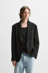 Blazer negro de corte regular fit, confeccionado en tejido con viscosa. Presenta cuello con solapas de muesca, manga larga con puños abotonados, bolsillo de vivo en el pecho, bolsillos de solapa en la cadera, bolsillo interior, aberturas en la espalda y cierre frontal con dos botones.