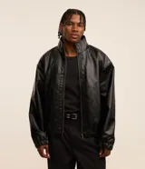 Campera negra de cuero sintético, corte boxy, con cuello alto, cierre frontal con cremallera, mangas largas y puños elásticos.