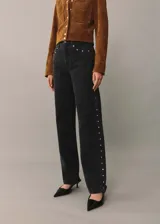 Pantalón de jean negro de corte recto con tachas plateadas en los laterales.
