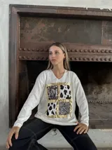 Remera roja de manga larga con cuello en V y estampado frontal con recuadros de animal print en dorado.
