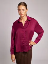 Camisa de satén color burdeos, con cuello solapa y escote en pico, de manga larga y corte holgado.