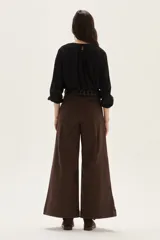 Jean de tiro alto y pierna ancha (wide leg) color marrón oscuro, con costuras visibles en el frente.