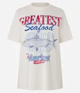 Remera t-shirt de algodón color crema, con cuello redondo y mangas cortas. Estampa frontal con la frase "Greatest Seafood" y un dibujo de un pez.