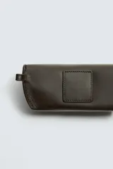 Funda de gafas de cuero marrón oscuro con cierre a presión y asa de mano.