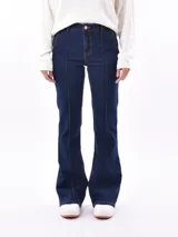 Jean de mezclilla azul oscuro, tiro alto, con costuras verticales marcadas en el frente de ambas piernas y corte acampanado (flare) en el bajo.