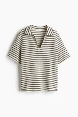 Top de punto con textura a rayas horizontales en blanco y negro. Tiene cuello camisero abierto, mangas cortas y corte holgado.