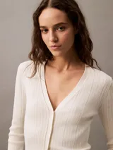 Remera blanca de punto acanalado con cuello en V y mangas largas. Corte ajustado al cuerpo.