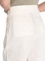 Pantalón de lino color blanco hueso, de tiro alto y pierna recta, con cierre cruzado y hebillas en los costados.