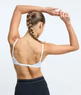 Top deportivo negro, tipo bralette, con escote en V y tirantes finos ajustables.