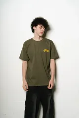 Remera verde oliva de corte regular fit, confeccionada en jersey de algodón. Presenta un pequeño logo bordado en el pecho y un estampado grande con el nombre de la marca en la espalda, ambos en color amarillo.