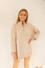 Sweater color ocre de lana de cordero con cuello alto abotonado y calce oversize.