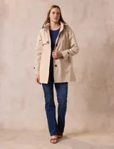 Gabardina impermeable color beige, marca Weatherproof, con abertura central con botones, bolsillos delanteros y capucha desmontable.
