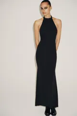 Vestido largo negro, corte recto, con cuello halter que se ata en la nuca y espalda descubierta.