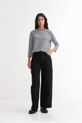 Pantalón de jean negro, tiro alto, de corte ancho y largo completo, con bolsillos cargo a los costados de las piernas.