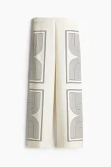 Pantalón de corte recto color crema con estampado geométrico en negro. Modelo de tiro alto con elástico en la parte posterior de la pretina y cierre oculto en un lateral.