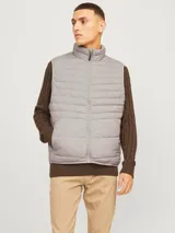 Chaleco puffer gris con cuello alto y cierre frontal con cremallera. Tiene bolsillos laterales y diseño acolchado horizontal.