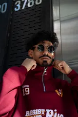 Buzo de algodón color bordó, estilo universitario, con cierre medio frontal y cuello alto. Estampado frontal con el texto "Since 19" y un ancla con laureles en amarillo y blanco.