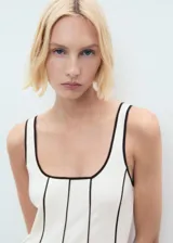 Vestido midi color crudo con tirantes anchos y escote cuadrado. Presenta ribetes negros en cuello, sisas y costuras verticales.