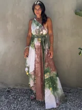 Vestido largo de tela fluida, color verde esmeralda con estampado abstracto en tonos turquesa y detalles dorados. Diseño asimétrico con un solo tirante tejido en el hombro.