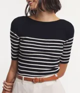 Blusa de punto con textura acanalada, escote barco y manga corta. Diseño a rayas horizontales en blanco y negro.