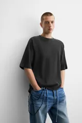 Camiseta negra de corte relaxed fit, cuello redondo y mangas cortas. Tejido de punto con textura acanalada y efecto lavado.
