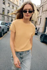 Top color amarillo de punto liso con cuello redondo y manga corta.
