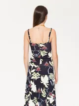 Top negro con estampado de flores blancas, rojas y amarillas, con breteles finos con volados y bordado JCH en el borde inferior izquierdo.