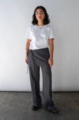 Falda gris con finas rayas verticales blancas, de corte mini y diseño cruzado con lazo lateral.