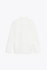 Camisa blanca de algodón con cuello con volantes y mangas largas con puños fruncidos.
