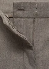 Pantalón largo de vestir color beige, de corte wideleg, tiro medio y tejido fluido. Presenta trabillas, bolsillos laterales y cierre frontal oculto con botón, gancho y cremallera. Tiene forro interior.