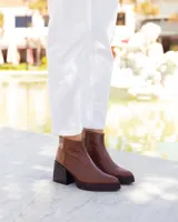 Botines de cuero marrón, hechos a mano en Uruguay, con plataforma delantera y taco ancho y alto de color negro. Presentan un detalle de textura de piel de reptil en la parte superior del talón y cierre lateral con cremallera.