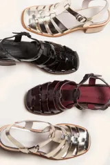 Sandalias de cuero color borgoña con tiras entrecruzadas, hebilla lateral y taco de madera.