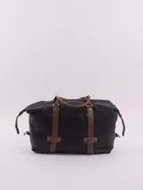 Bolso de viaje negro con detalles en cuero marrón, doble asa de mano y cierre superior con cremallera.