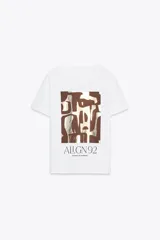 Camiseta blanca de algodón con cuello redondo, manga corta y estampado metalizado en el frente con formas abstractas y texto "AILGN92 SHAPES OF HARMONY".