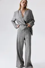 Pantalón de vestir gris claro, de tiro alto, con bolsillos laterales y traseros. Piernas amplias con pliegues delanteros y traseros. Confeccionado en tejido liviano de mezcla de lino y viscosa.