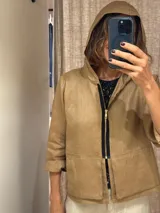 Chaqueta color beige de lino, con capucha, cierre frontal con cremallera negra, bolsillos laterales y mangas 3/4.