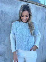 Sweater celeste con mangas blancas, tejido con ochos en la parte delantera y liso en la parte trasera.
