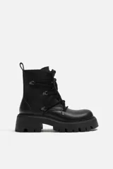 Bota de cuero negra con cordones, cordonera con nueve pasados, tirador trasero y suela track con volumen.