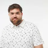 Remera polo blanca de piqué con estampado de palmeras, tablas de surf y sombrillas.