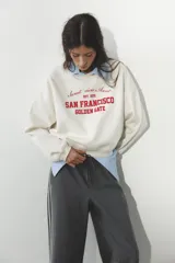 Sudadera azul marino de cuello redondo y manga larga con estampado frontal que dice "New South Wales Sydney 1985 Bondi Beach" en color blanco.