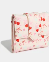 Billetera pequeña con solapa, color crema con estampado de corazones rojos, moños rosas y cerezas.