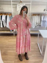 Vestido midi rosado con estampado cachemir en tonos beige, corte holgado, cuello mao y mangas 3/4 acampanadas. Cierre frontal con botones.