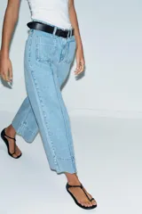 Jeans de tiro alto con corte wide leg cropped, confeccionados en denim de lavado claro. Presentan costuras marcadas en el frente, bolsillos de plastrón delanteros y cierre frontal con cremallera y botón.