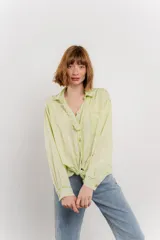Camisa color crema de manga larga con cuello camisero y detalles de encaje en el escote. Se ata en la parte delantera.